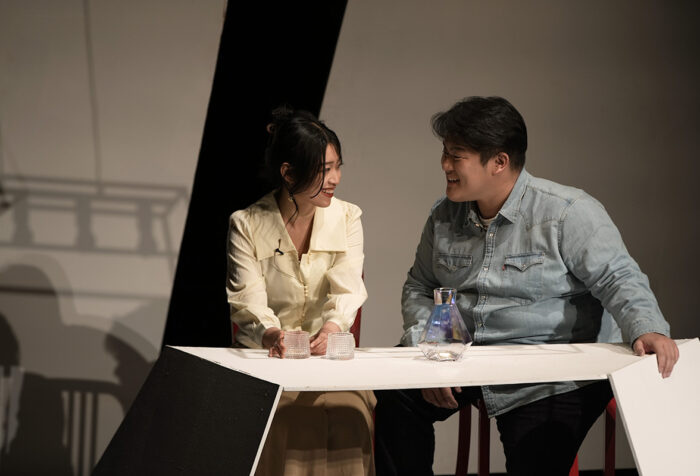 Wisteria Deng and Yuning Su sit at a table during a performance of Constellations in December 2023