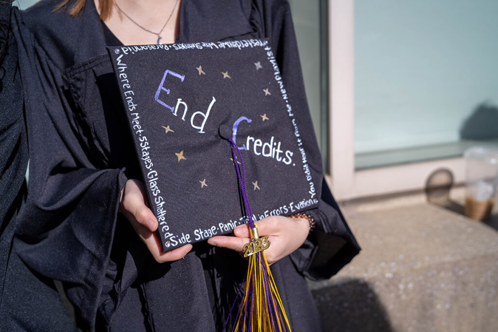 Student holds mortarboard that reads "End Credits"
