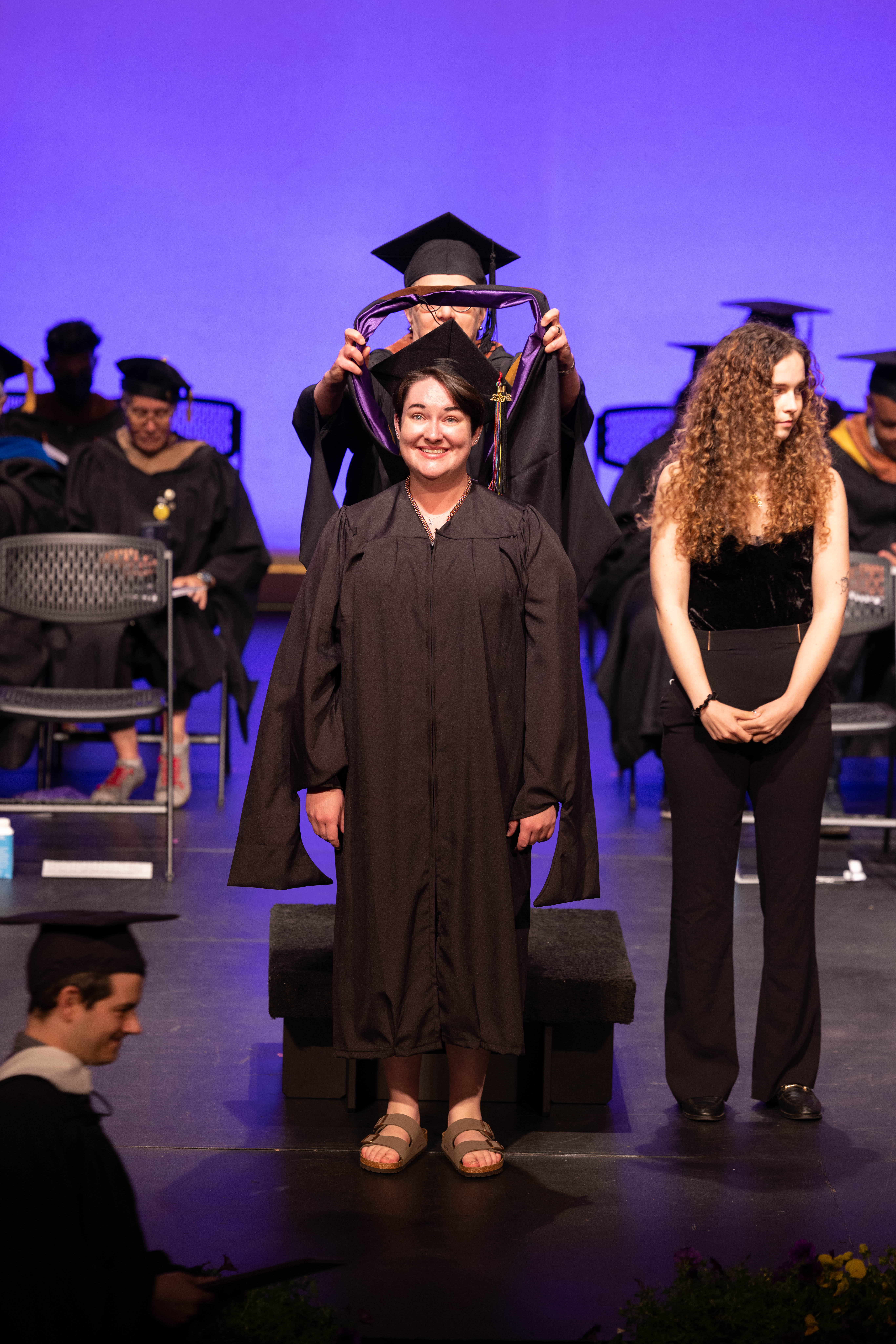 A graduation stands on stage receiving her stole