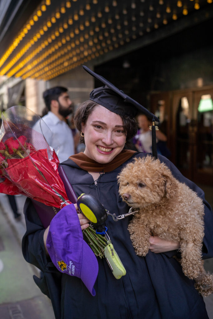 A graduate with flowers and a dog