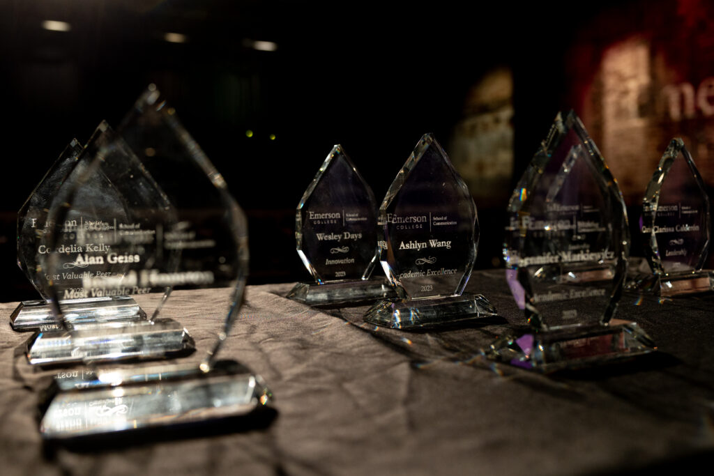 Dozens of translucent glass 2023 SOC Award trophies with frost engravings of names and categories, rest on a table inside the Black Box Theater.  