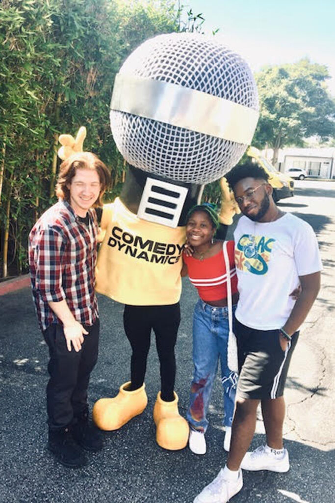 Three students pose with guy dressed as a giant microphone