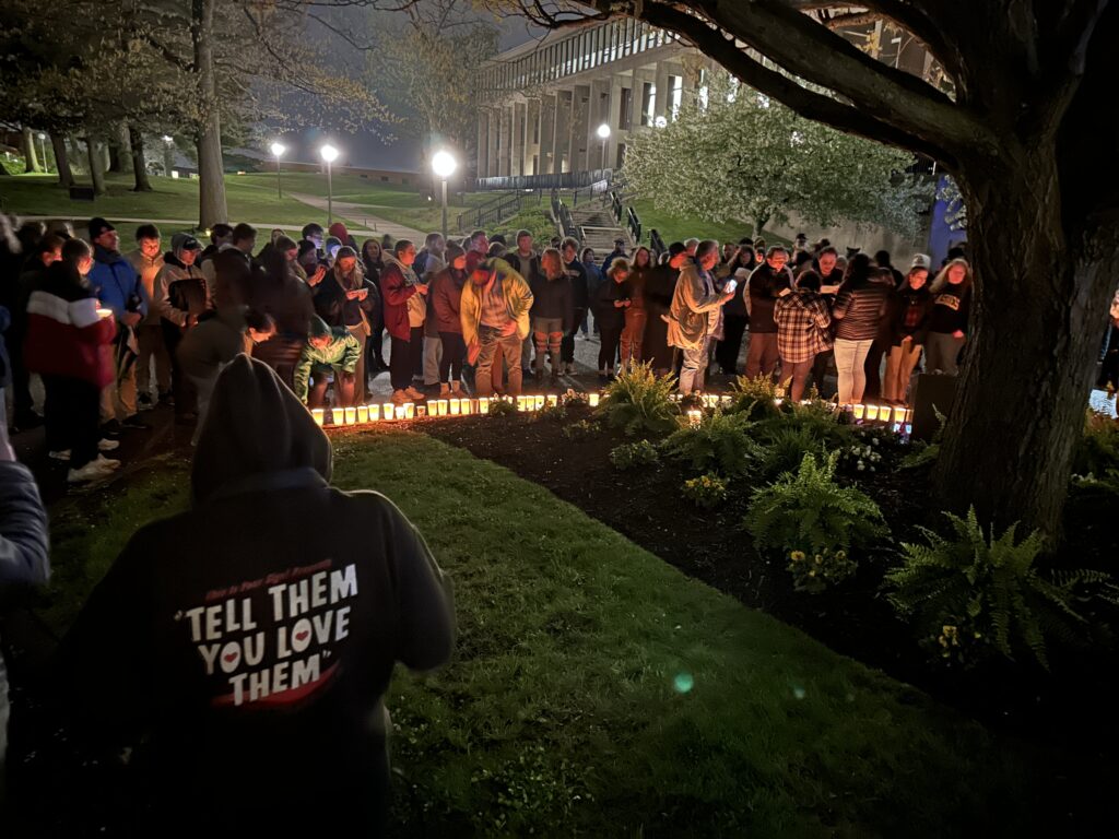 People participate in a nighttime vigil in remembrance of the Kent State shootings in 1970. There are lit candles near the group