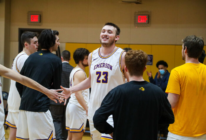 Jarred Houston, surrounded by teammates on the court, smiles and slaps hands with one of them