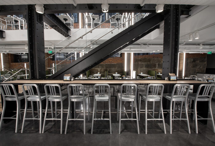 bar stools lined up at long counter, stair case in background
