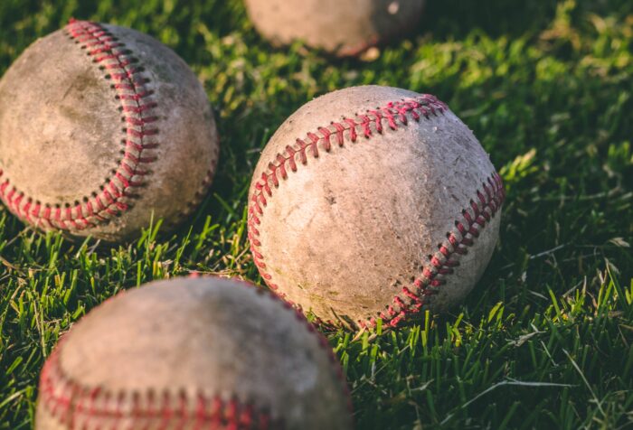 Four baseballs lying in green grass.