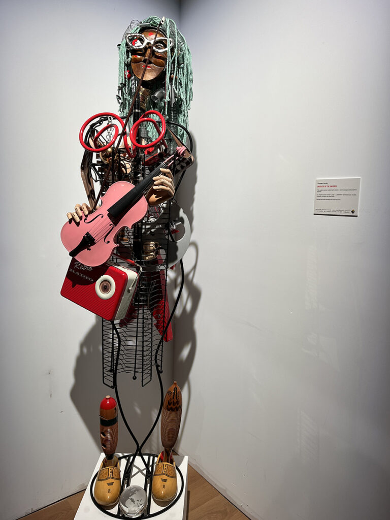 multimedia sculpture of woman holding pink violin, radio