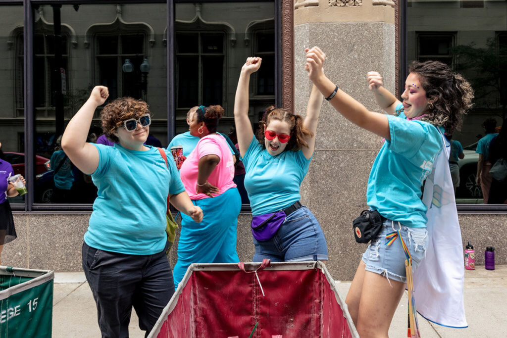 students in blue t shirts dance around a rolling bin