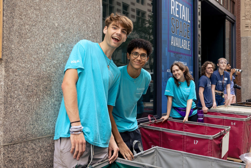 students in blue t-shirts line up on street with rolling bins