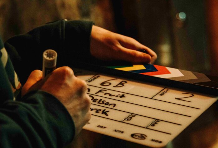 A person writes film information on a clapperboard.