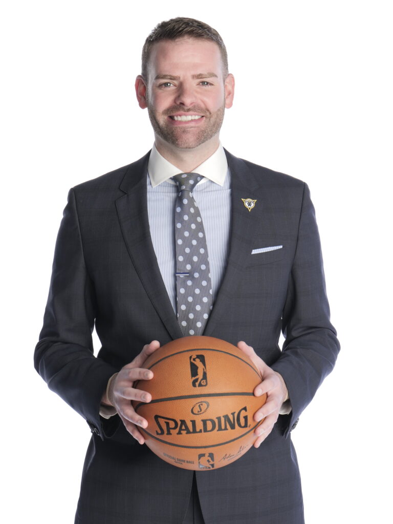 Chris Taylor holds a basketball while wearing a suit