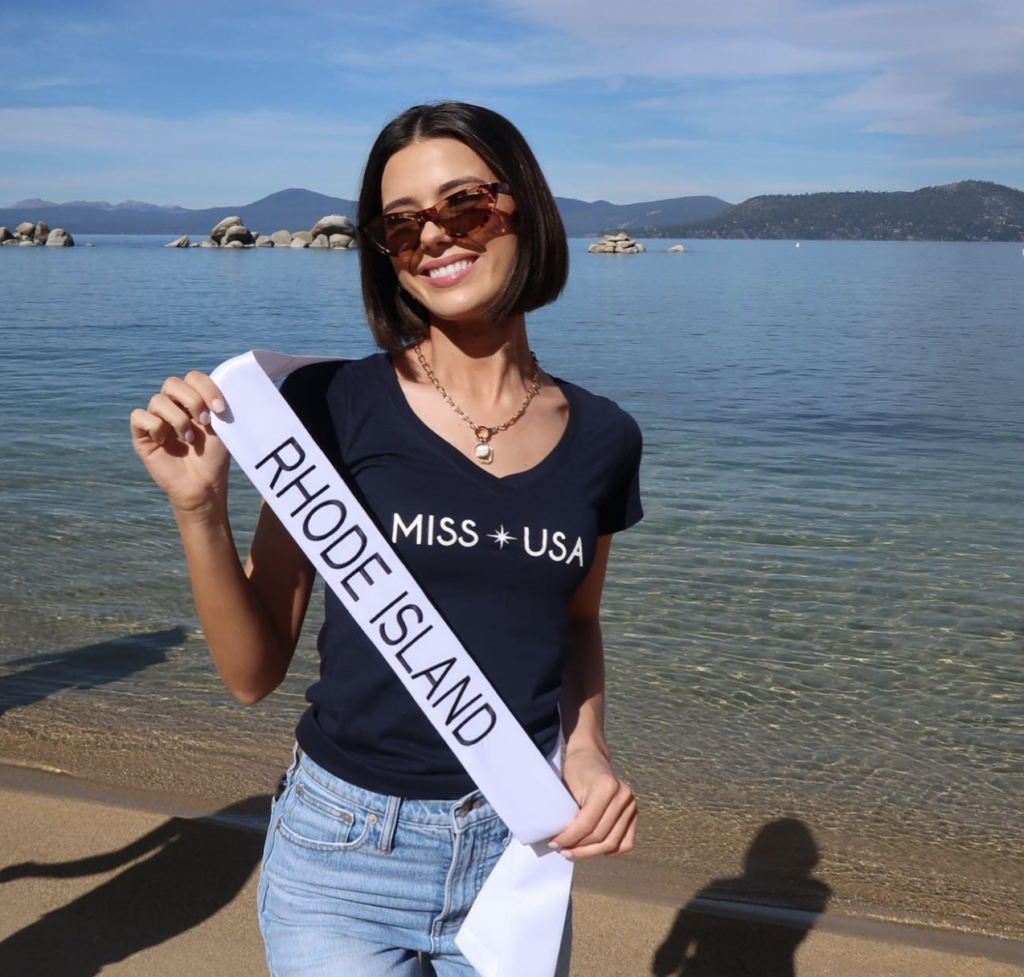 Mary Malloy holds her Miss Rhode Island sash by water behind her