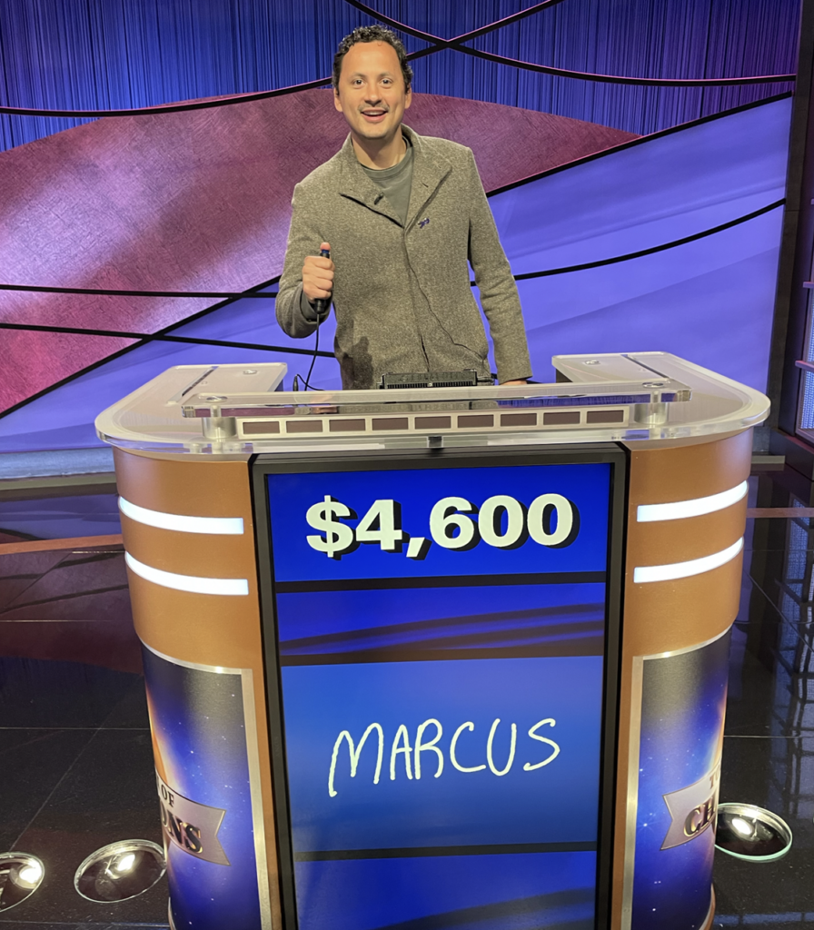 Marcus Brown stands behind a Jeopardy! contestant podium