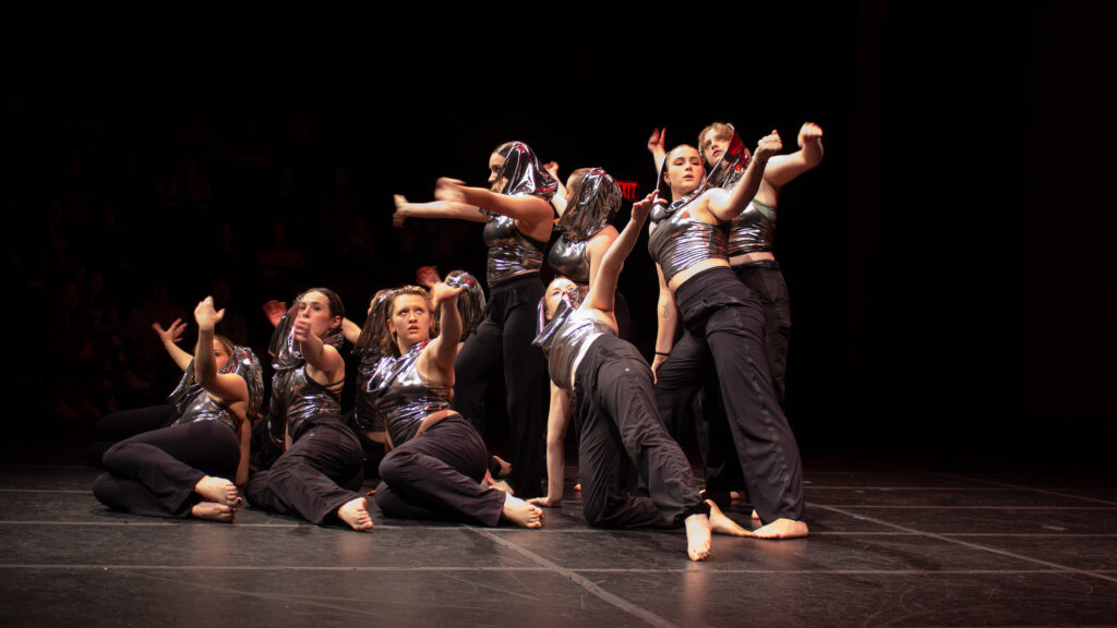 Dancers lean in together on stage