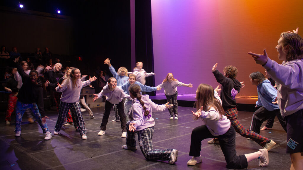 Two groups of students dance in pajama-like clothing in a West Side Story Jets versus Sharks way