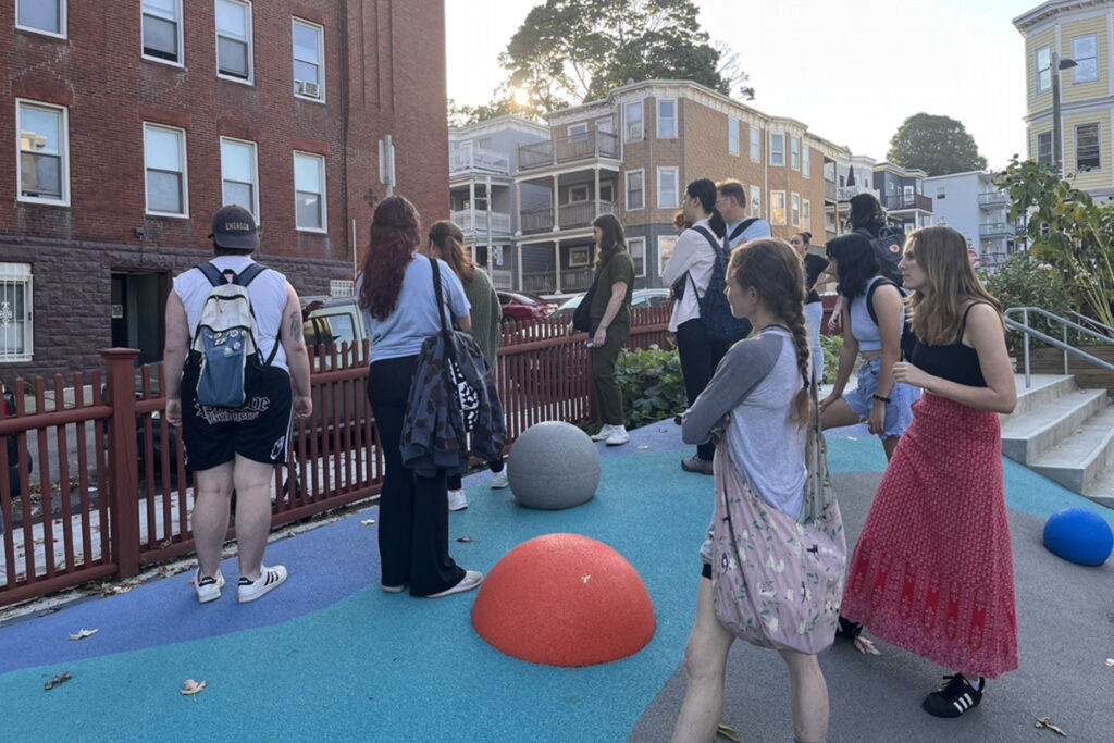 students stand in playground surrounded by triple-deckers
