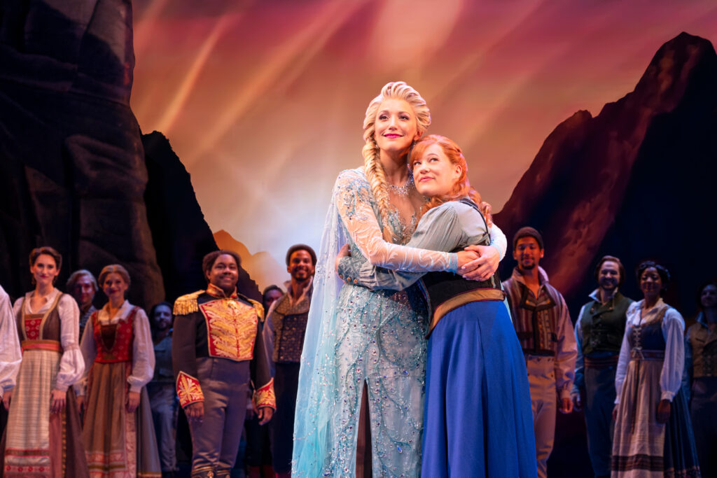 Caroline Bowman as Elsa hugs Lauren Nicole Chapman as Anna on stage
