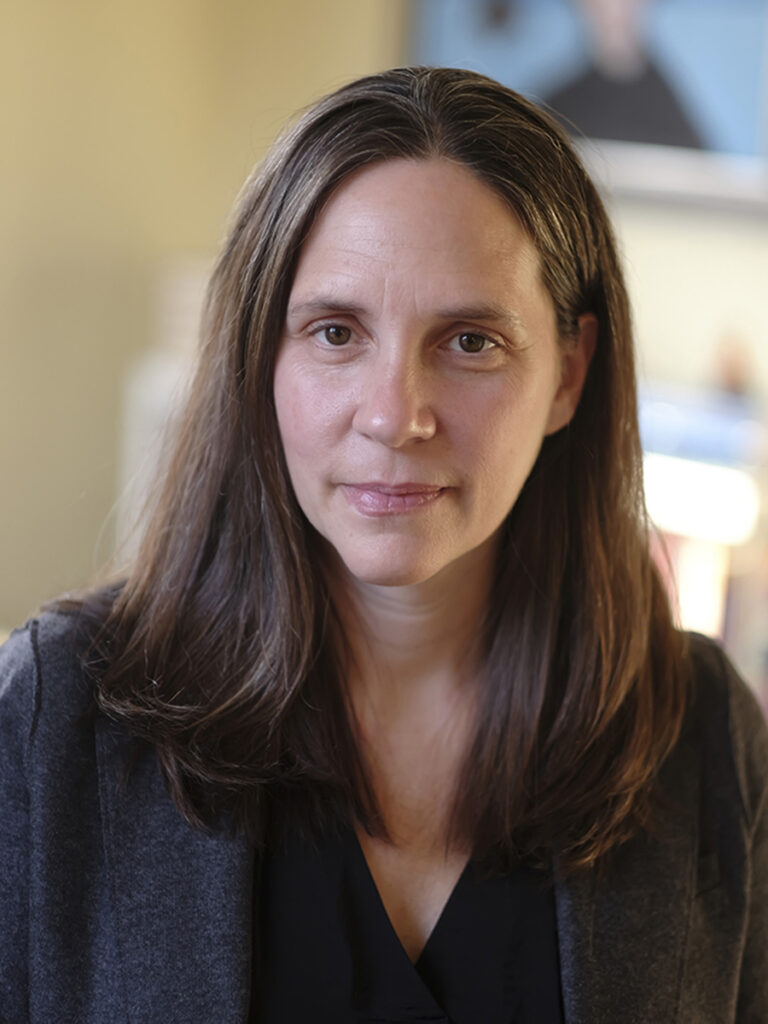 Woman with long brown hair, wearing dark shirt