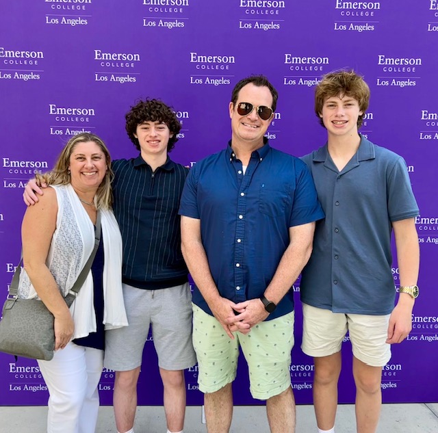 The four members of the Arnold family in front of a Emerson College sign