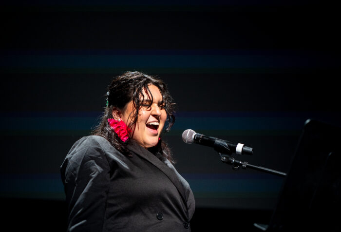 A person sings loudly into a microphone on stage