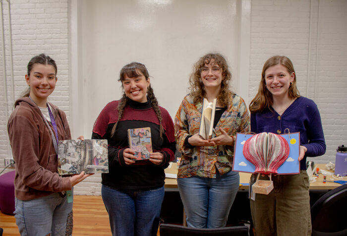 Four people display the upcycled art that they made