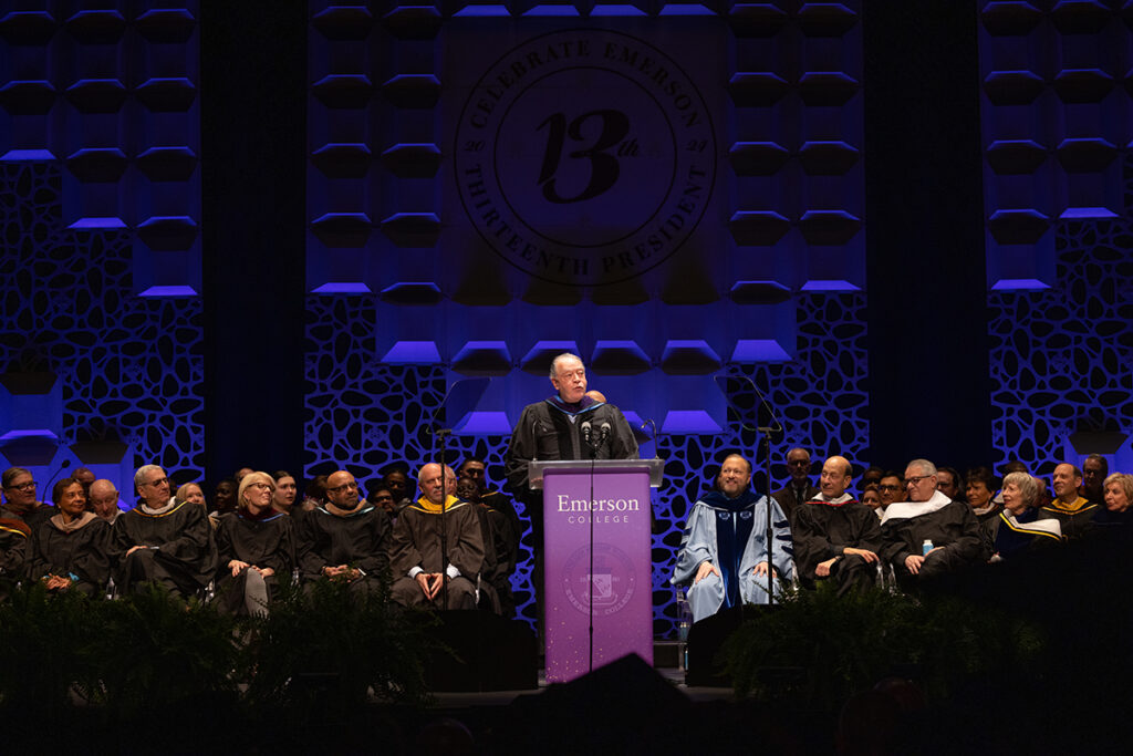Man in black robe stands at podium as people in black robes look on