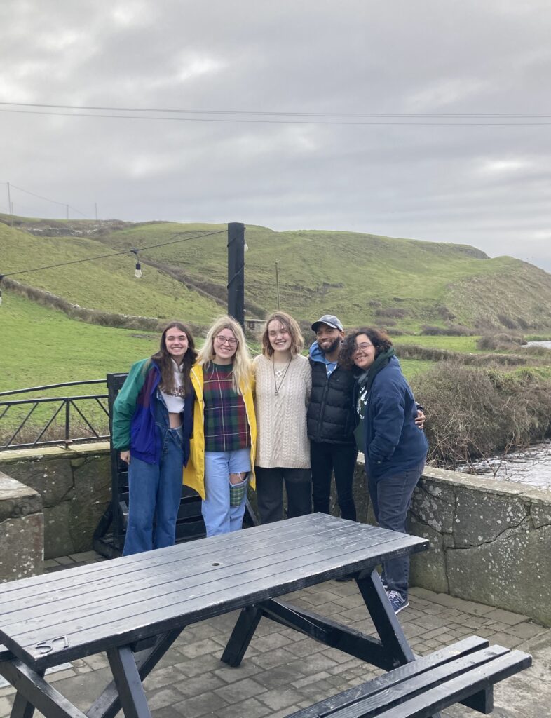 Standing in front of an Ireland hillside is Kayla Armbruster, Olivia DeCesare, Stella Del Tergo, Deion Hawkins, and Braelyn Spitler