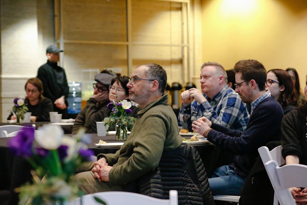 faculty sit around tables in the Bordy Theater