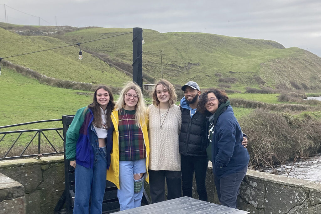 Five people stand together in front of an Ireland hillside