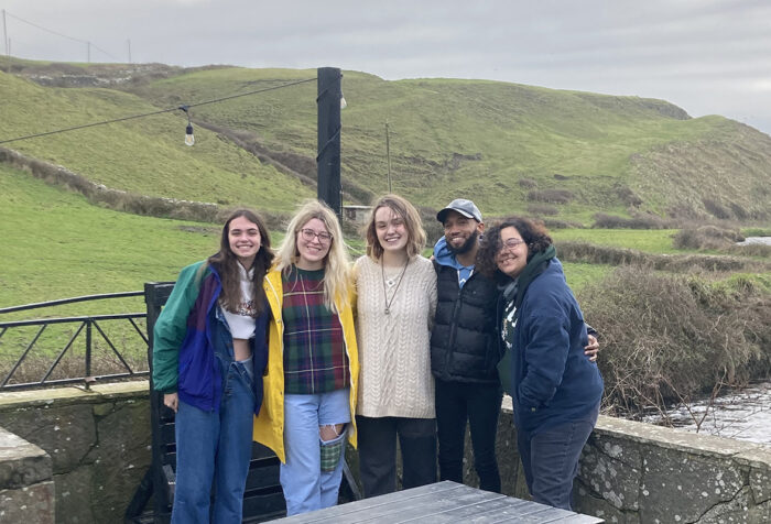 Five people stand together in front of an Ireland hillside