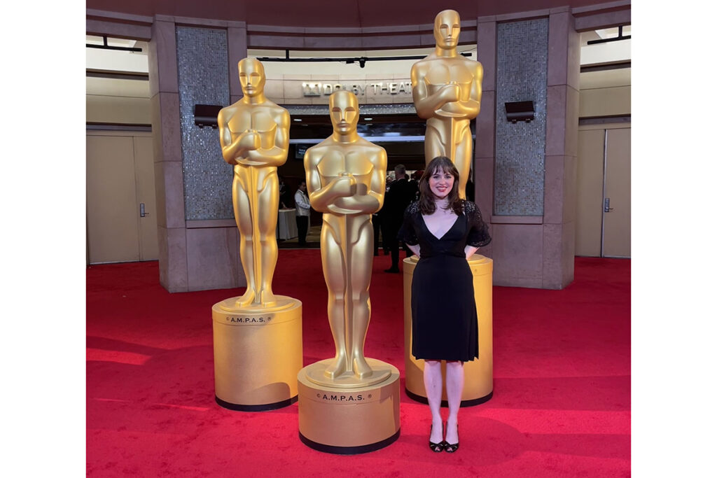 Ruby Brooks standing in front of three live size Academy Awards