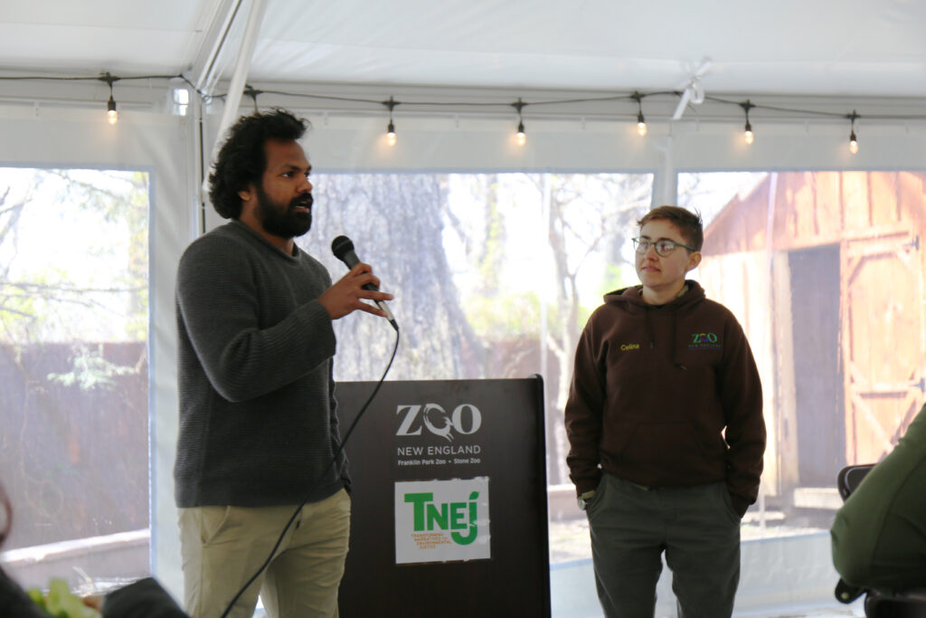 Performing Arts Assistant Professor Tushar Mathew addresses the audience under a tent