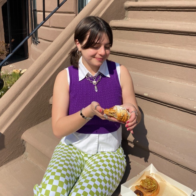 Anna Arriaga ’24 sits on a city stoop, eating.