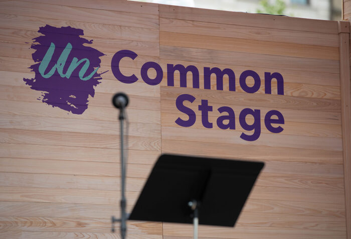 microphone stand and music stand in front of a wooden backdrop reading unCommon Stage