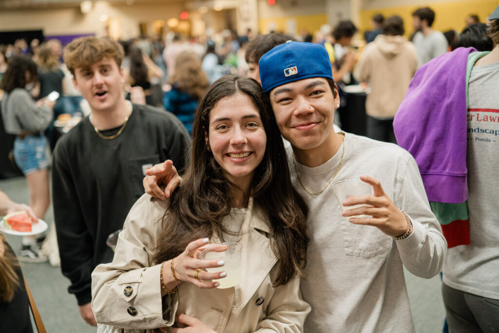 Two people pose for the camera while smiling and holding drinks