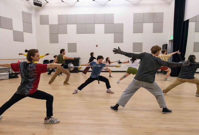 Students lunge with swords during a class