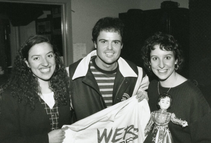 Donny Osmond holds up a WERS shirt with two students next to him
