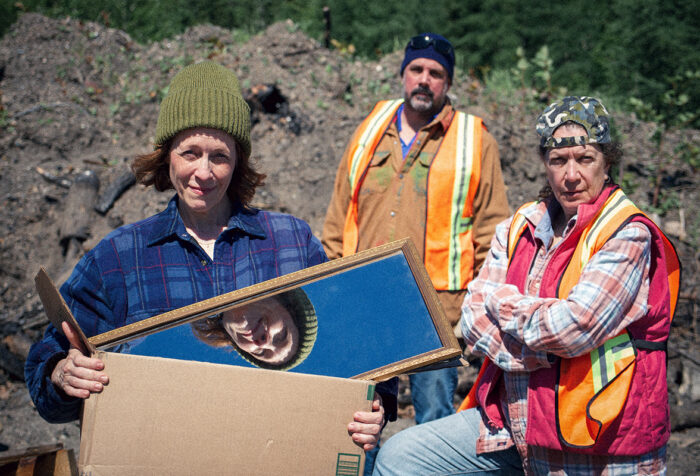Promotion photo for Salvage. Three people stand in a dump.