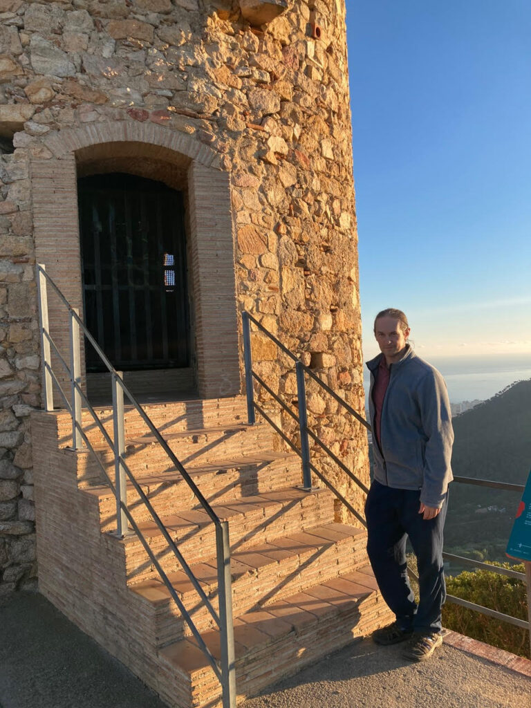 Adam Franklin-Lyons stand at the steps of a medieval lookout fort 