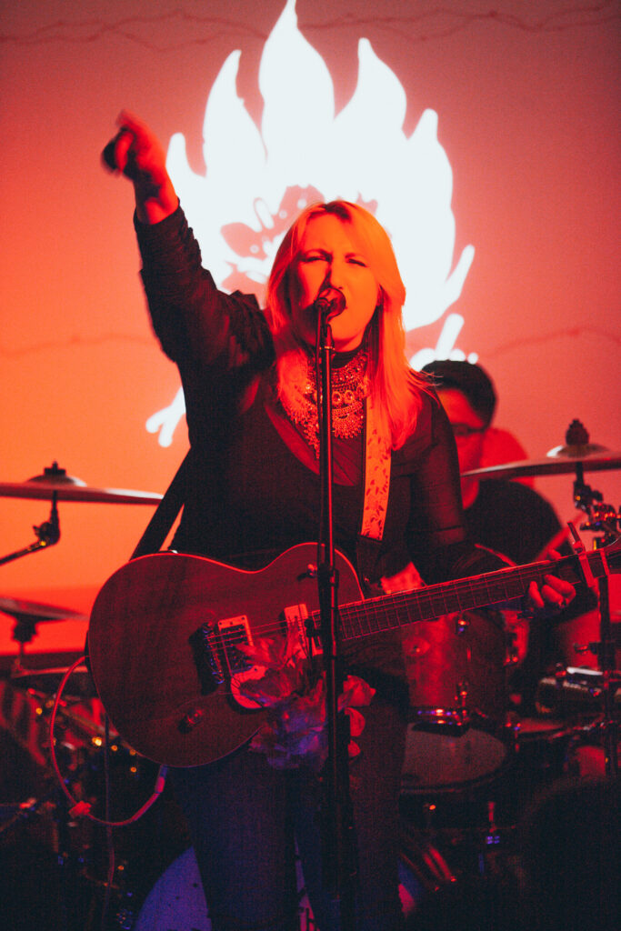 Alexa Lash raises her hand while singing on stage