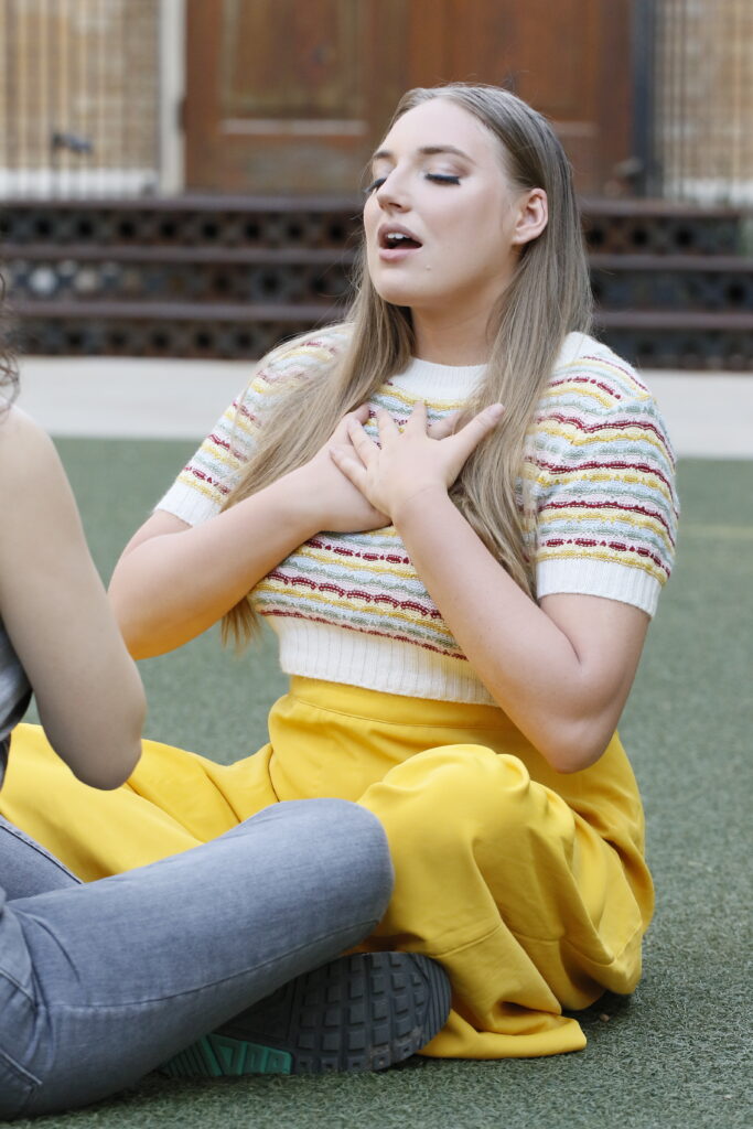 Alicia Topolnycky holds her hands to her chest while doing a breathing exercise with another person