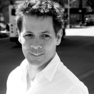 Black and white photo of man with short-cropped hair in a white collared shirt.