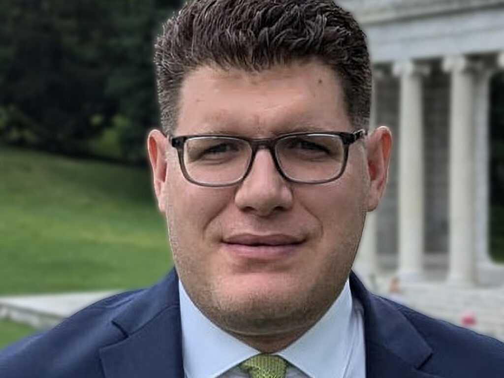 man wearing glasses, blue jacket, green tie