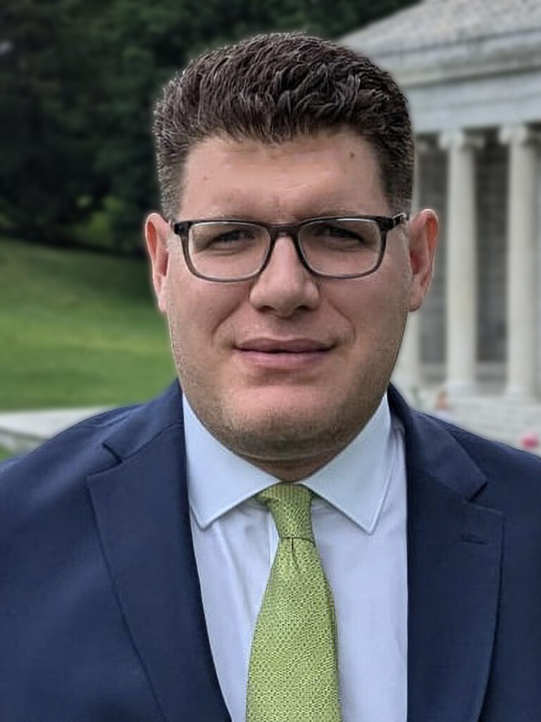 man wearing glasses, blue jacket, green tie