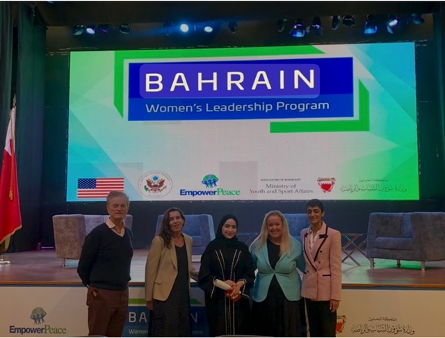 Five people stand in front of a large projection screen that says: Bahrain 
Women's Leadership Program