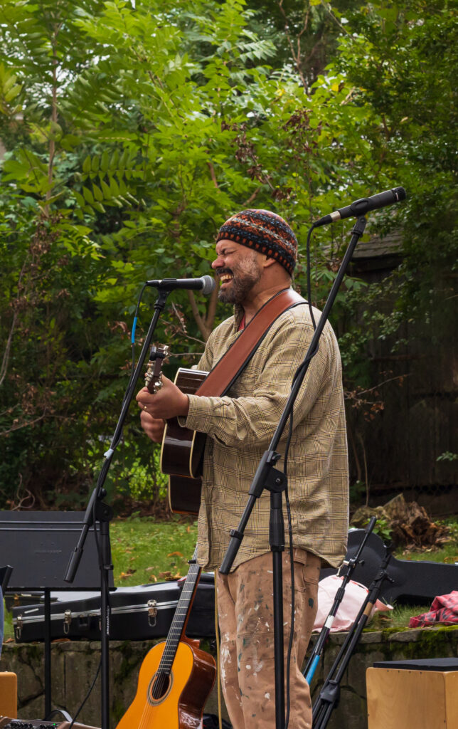 Nejem Raheem plays guitar and sings in front of a microphone