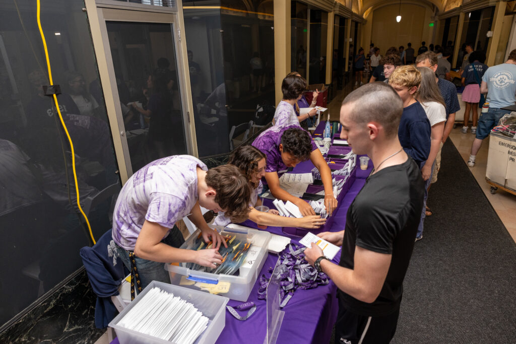 New students speak with orientation leaders at a table inside the Little Building