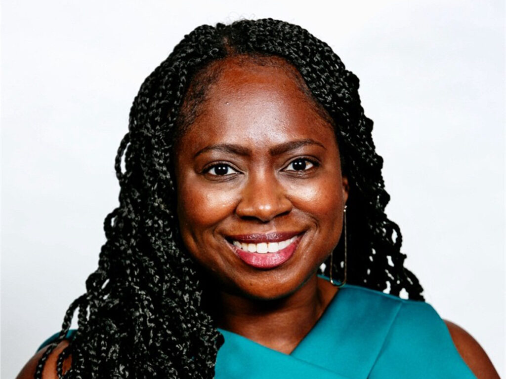 Head shot of woman with braids, teal-colored top