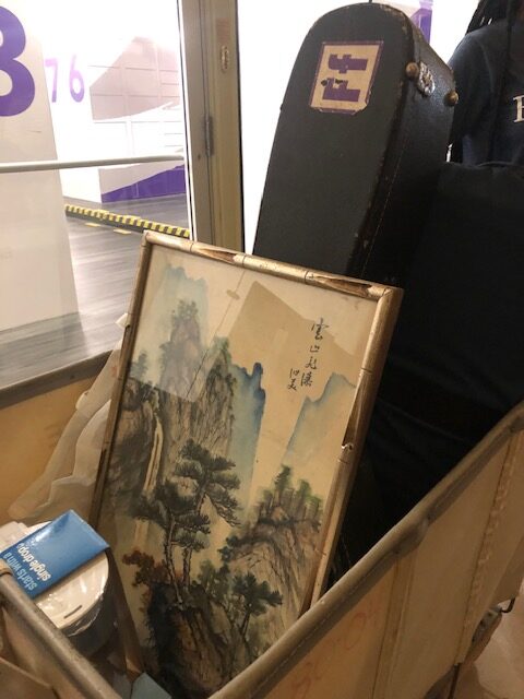 A Japanese still portrait and guitar in case are in a cart