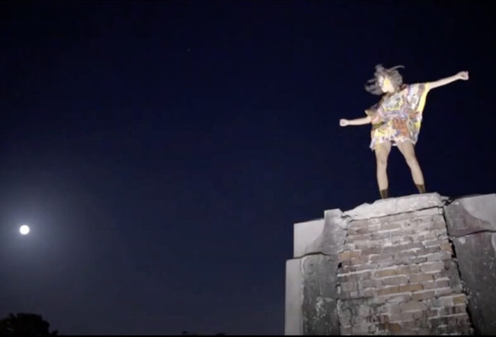 A person stands atop of a bluff with arms stretched out